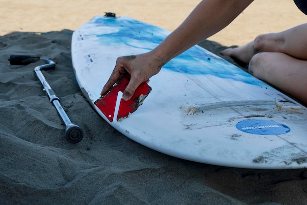 Detail shot of young woman preparing her board for adapted surfing competition