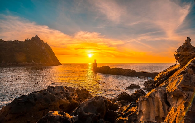 Detail of the sun behind the lighthouse at sunset in the town of Pasajes San Juan