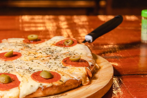 Detail view of a pepperoni pizza on a wooden table