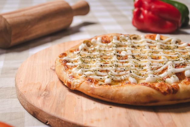 Detail view of a pizza with lots of cheese on a table with a checkered tablecloth