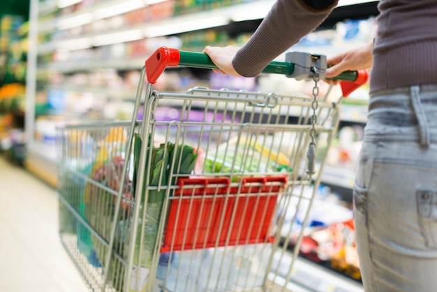 Detail of a woman driving her shopping cart in a grocery store