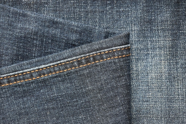 Detailed abstract texture of dark blue denim cloth Background image of old used denim trousers fabric