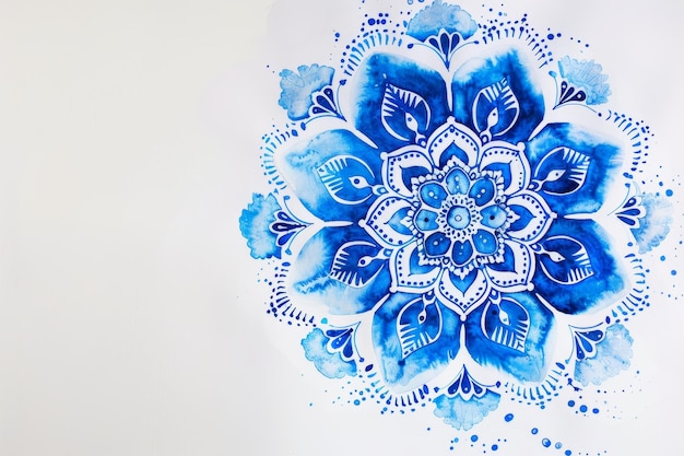 A detailed watercolor mandala design in shades of blue painted on a white paper background Intricate mandala design in shades of blue on a clean white backdrop