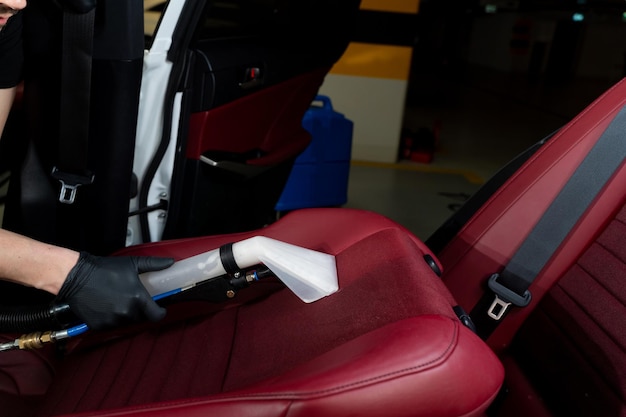 Detailing car seats with the help of vacuum extractor Cleaning car backseat with special vacuum nozzle