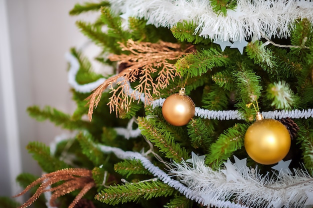 Details of Christmas tree decor in gold close-up and copy space. Christmas tree branches and  toys