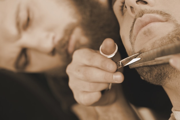 Details matter. Closeup cropped shot of a barber cutting beard of his client carefully with scissors