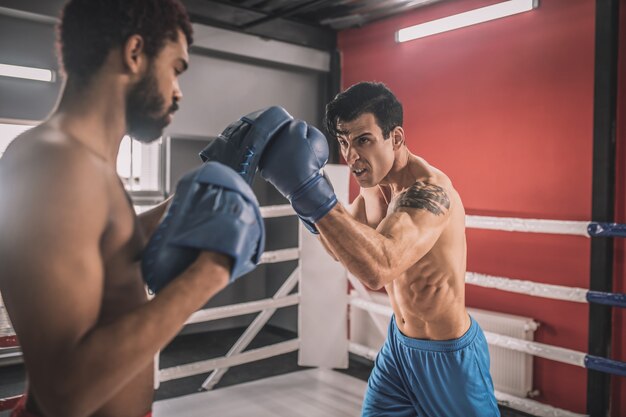 Determination. Young men fighting on a boxing ring and looking determined