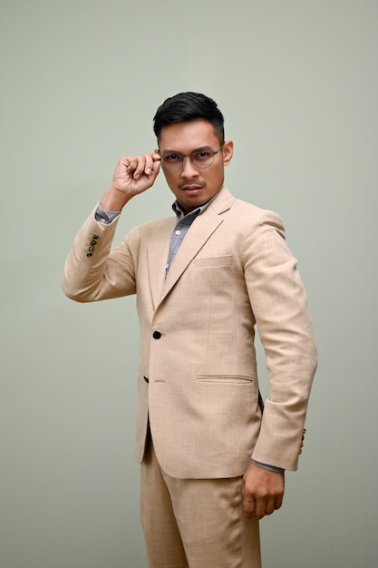 Determined Asian businessman touching his glasses while standing against an isolated background