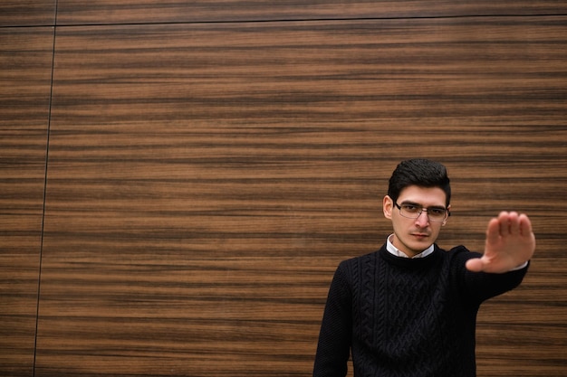 determined concentrated serious business man. modern smart professional worker. stop gesture. wood texture wall background. outdoors street. copyspace concept