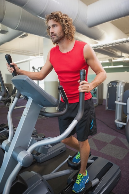 Determined man working out on x-trainer in gym