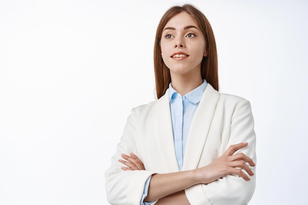 Determined professional office ceo woman wearing business suit cross arms on chest looks aside with hopeful and confident face white background