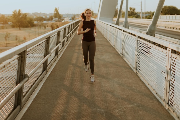 Photo determined runner jogs along a sunlit bridge during the golden hour blending fitness and serenity in an urban landscape