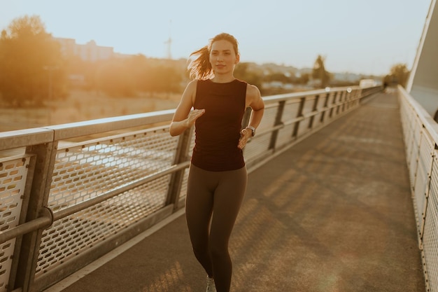 Photo determined runner jogs along a sunlit bridge during the golden hour blending fitness and serenity in an urban landscape