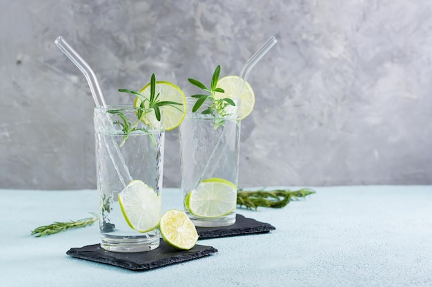 Detox drink water with lime and rosemary in glasses with eco straw on the table Homemade cocktails