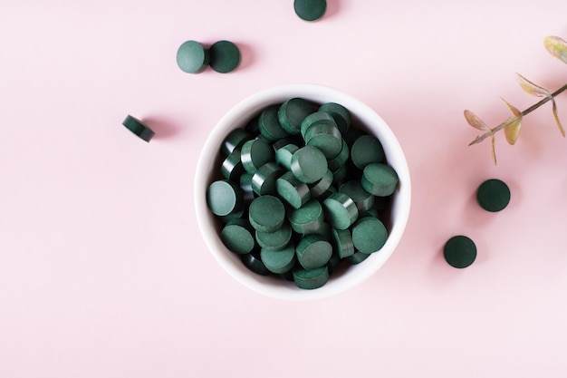 Detox products Spirulina seaweed in pills and matcha tea powder in bowls Top view Closeup