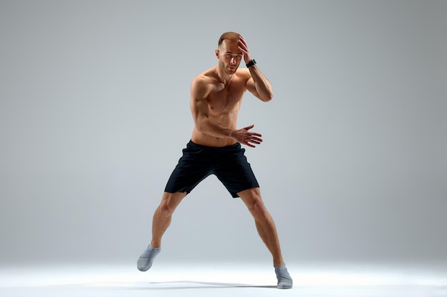 Developing endurance Male athlete in motion isolated over gray studio background Maintaining health and strength Concept of sport healthy lifestyle motion