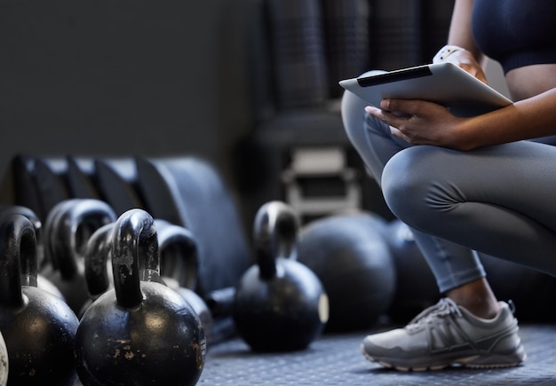 Developing a new circuit for her clients Closeup shot of an unrecognisable woman using a digital tablet alongside kettlebells in a gym