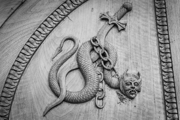 Devil snake symbol Fantasy magic creature on an old door 12th Century Abbey in Italy