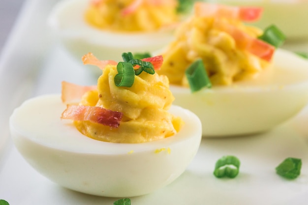 Deviled eggs garnished with green onions and bacon.