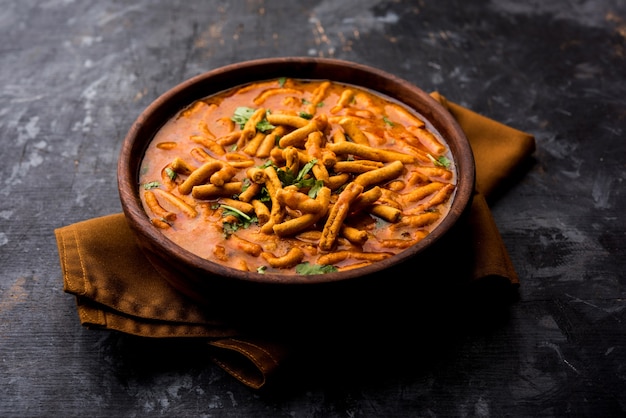 Dhaba style Sev bhaji, sabzi, curry made in tomato curry with gathiya or ganthia shev, served in a bowl or karahi, selective focus