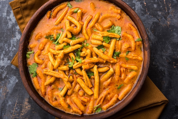 Dhaba style Sev bhaji, sabzi, curry made in tomato curry with gathiya or ganthia shev, served in a bowl or karahi, selective focus