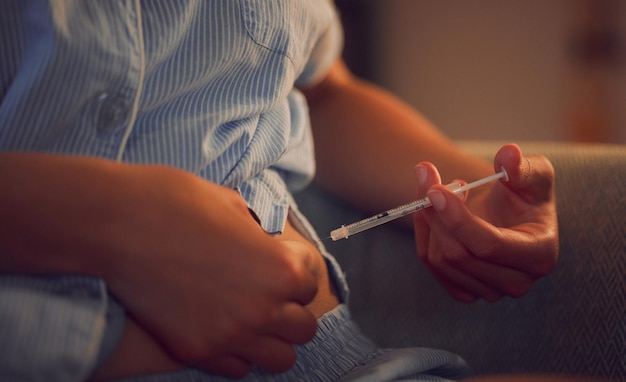 Diabetes diabetic and insulin injection of a woman with a chronic disease late at night Hands of a female taking her daily shot of treatment with a syringe in the evening at home