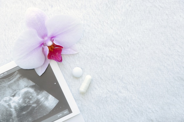 Diagnosis of ultrasound with pills and flower on a white background.