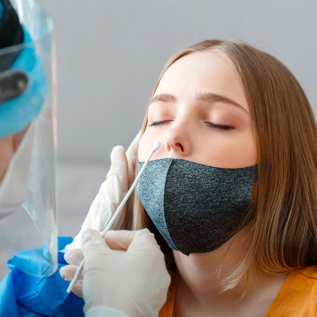 Diagnostics testing patients coronavirus covid 19 Doctor in protective medical mask taking PCR test nasopharyngeal culture to woman Nurse take saliva sample test through nose with cotton swab