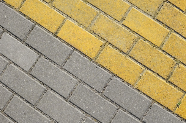 Diagonal grey and yellow paving slabs top view. Bricks as street road, paving stone texture. Abstract dual color paving stone background.