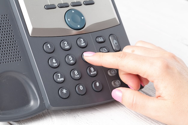 Dialing voip phone in the office, keyboard and monitor detail 