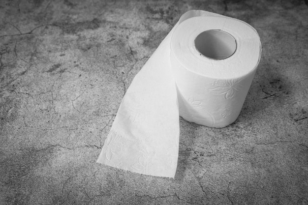 Diarrhea, constipation or digestive problems concept. Soft toilet paper roll on textured gray wall for article, banner or advertisement.