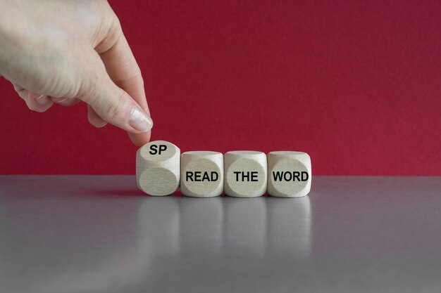 Dice form the expressions spread the word and read the word Businessman hand Beautiful gray table