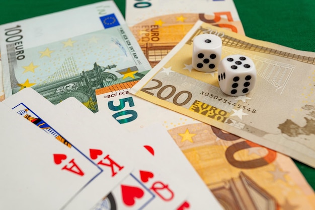 dice playing cards on a green cloth in a casino dollars and euro bills