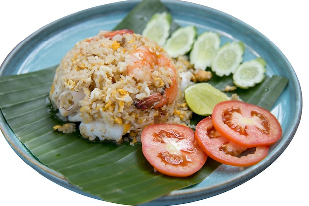 Die cut of Shrimp and squid fried rice with sliced tomatoes and cucumbers on banana leaf on white isolated