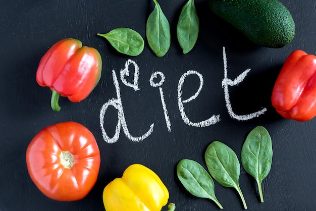 Diet chalk inscription Spinach leaves tomato yellow and red pepper around