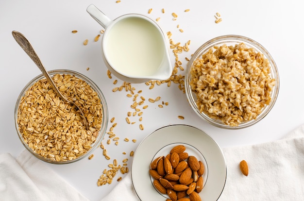 Diet food menu for breakfast with oats bowl with nuts and milk jar on wooden board