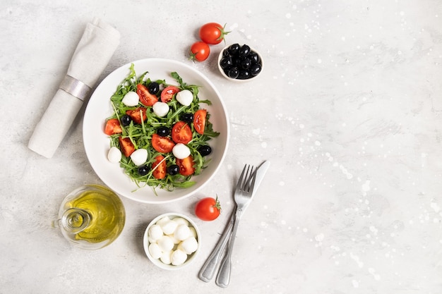 Diet food salad with arugula mozzarella tomatoes and olives olive oil