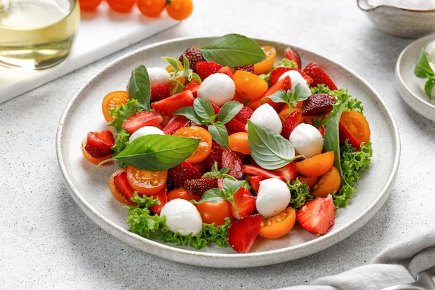 Diet and healthy salad with cherry tomatoes mozzarella cheese strawberry basil and olive oil