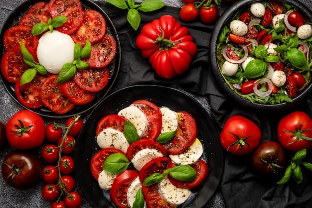 Diet and healthy tomato salads with arugula cherry tomatoes burrata mozzarella cheese and olive oil on dark background Top view flat lay