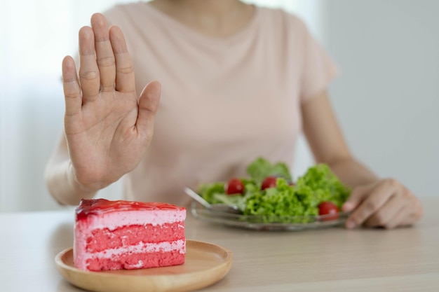 Diet and lose weight concept Woman reject to eat strawberry cake and choose eat salad for good health and slim shape