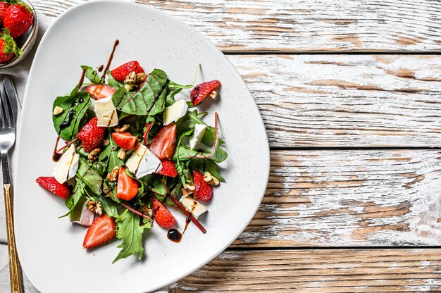 Diet salad with brie cheese, strawberries, nuts, chard and arugula . 