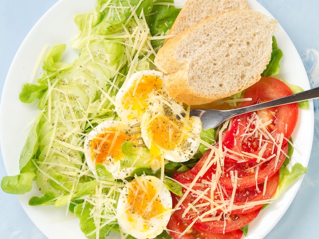 Diet salad with soft boiled eggs, cheese and vegetables - tomatoes, lettuce. 