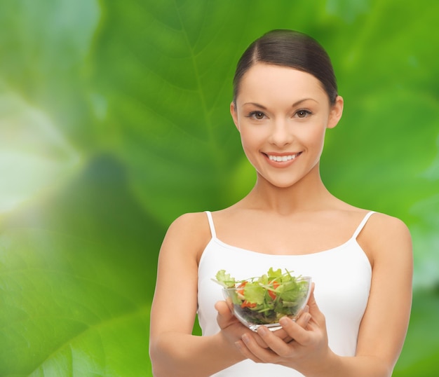 diet and sport concept - healthy woman holding bowl with salad