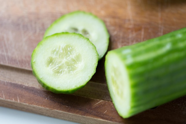 diet, vegetable food, cooking and objects concept - close up of cucumber on wooden cutting board