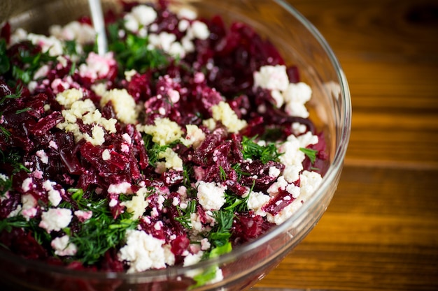 Dietary salad of boiled beets with walnuts and cottage cheese on a wooden table