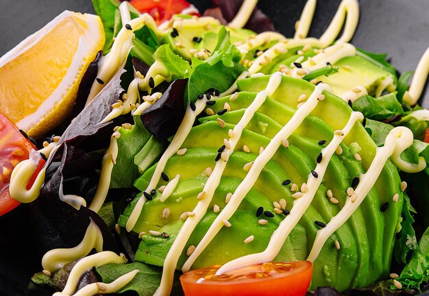 Dietary salad with avocado on a black plate