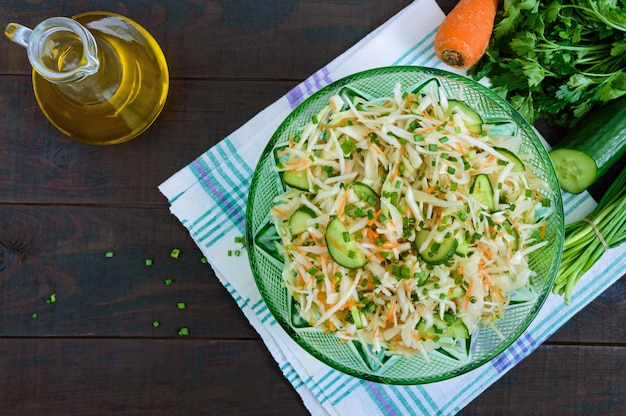 Dietary salad with cabbage, cucumber, carrot, greens. Juicy spring salad with fresh vegetables on a wooden table. Proper nutrition.