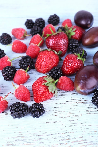 Different berries and plums on wooden table closeup