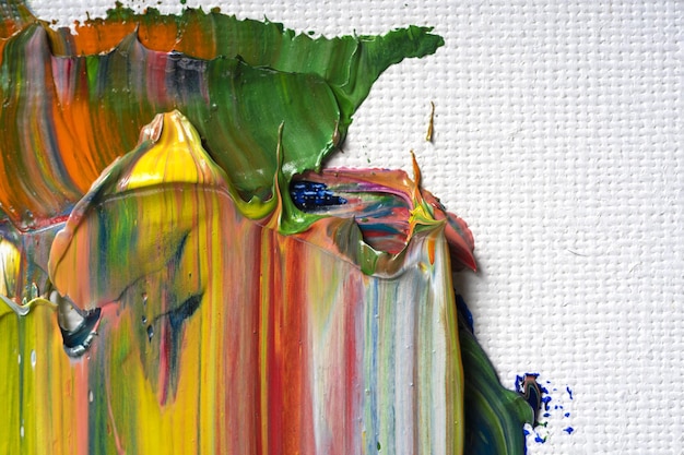 Different bright colors of oil paints are mixed on a palette close-up.