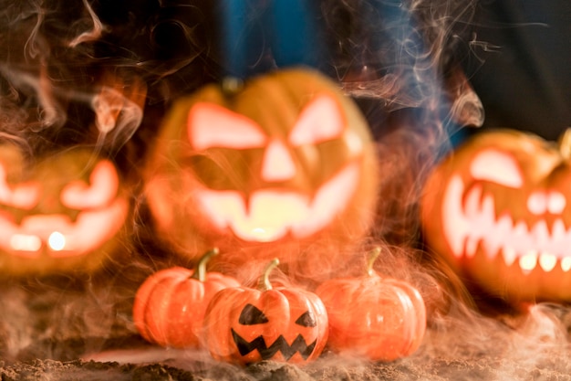 Different carved pumpkins with smoke